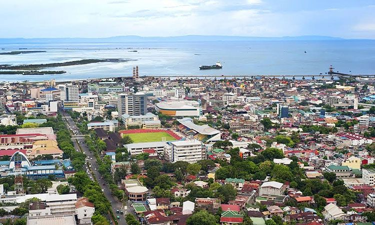 A big piece of land with houses and buildings all over, surrounded by a body of ocean.